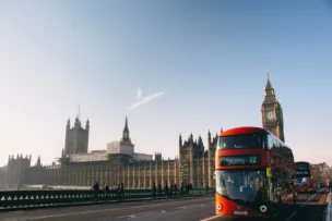 An image of the houses of parliament in London, with Big Ben and a red London bus in view.