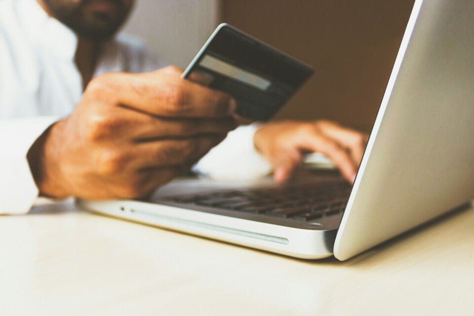 A man using his bank card and laptop to make an online payment