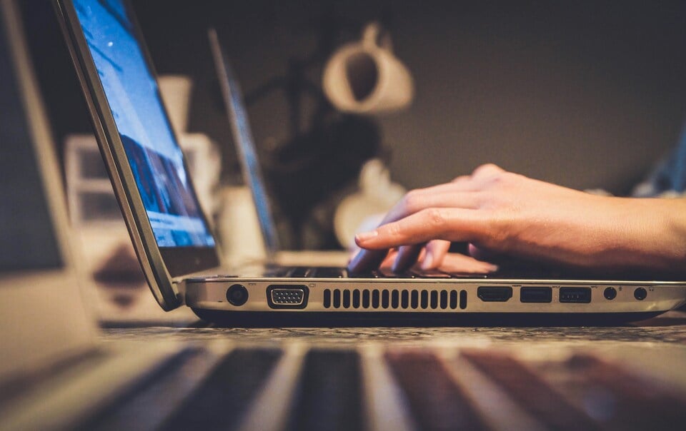 An image of somebody using a laptop from a side angle