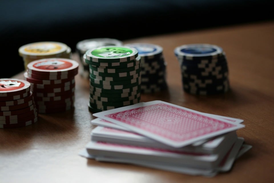 A stack of playing cards beside some poker chips