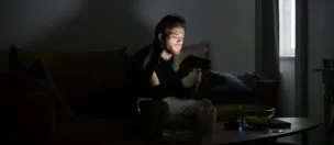 A young man gaming on his phone in the dark