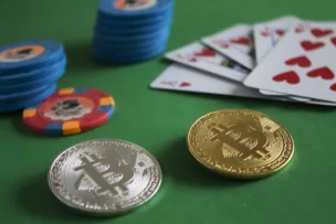 Crypto coins, poker chips and playing cards laid on a green poker table