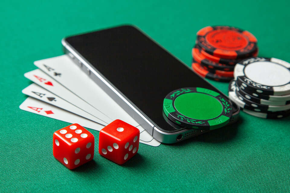 Mobile phone and game cards with chips and dice on a green gaming table