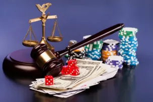 A gavel on top of a judge's desk alongside money, dice and poker chips