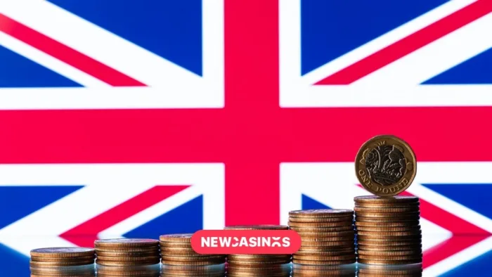 UK Gambling Shares Dive as Budget Tax Talks Intensify A Union jack flag with piles of coins stacked in front. Featuring the NewCasinos logo