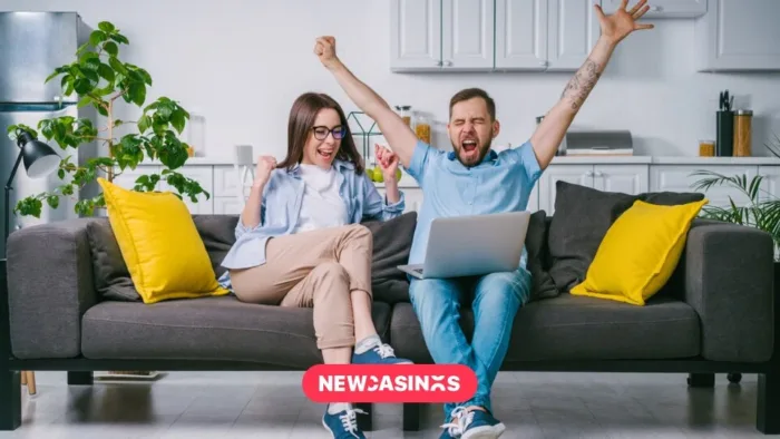 Exploring Slingo and Other Casual Games Gaining Popularity in the UK A couple sitting on their couch celebrating with an open laptop.