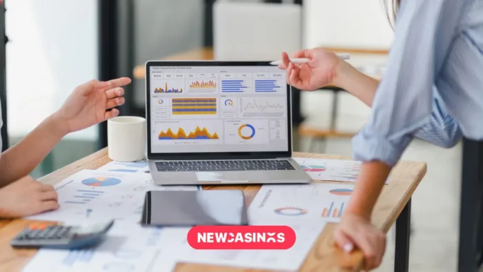 New Structures and New Insights in UK Gambling Regulation Screen showing graphs and other graphics with papers across the table and two business people talking.